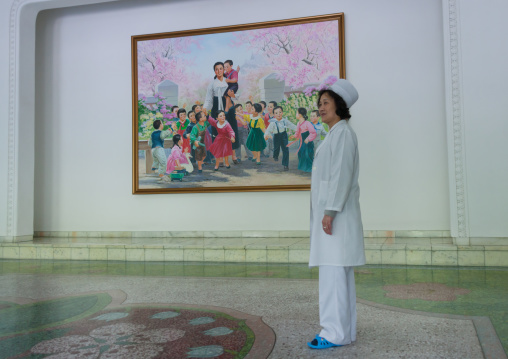 North Korean school employee in front of a propaganda poster with Kim Jong suk and North Korean children, Pyongan Province, Pyongyang, North Korea