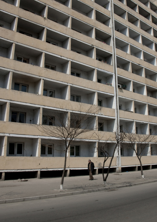North Korean man walking in the street in front a building, Pyongan Province, Pyongyang, North Korea