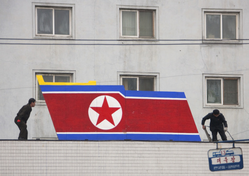 North Korean men setting a giant flag on a building, Pyongan Province, Pyongyang, North Korea