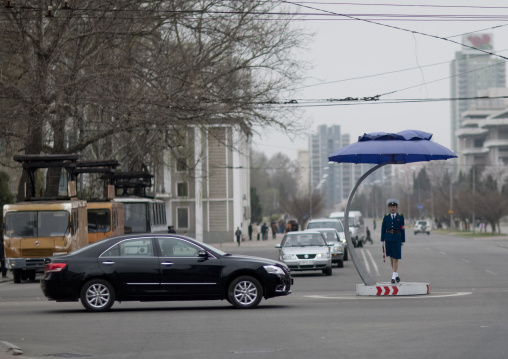 North Korean traffic security officer in blue uniform in the middle of cars, Pyongan Province, Pyongyang, North Korea