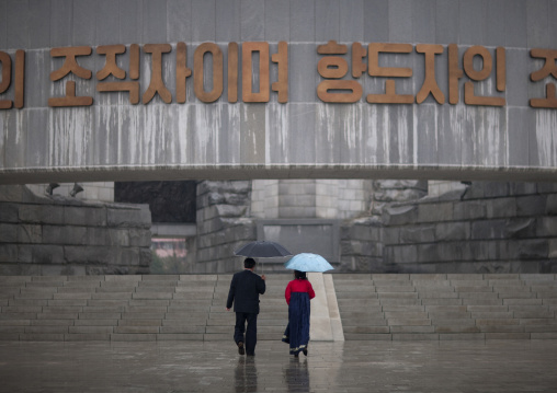North Korean man and woman under an umbrella going to the monument to Party founding, Pyongan Province, Pyongyang, North Korea