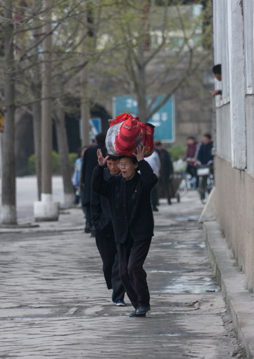 North Korean woman carrying heavy stuff on her head in the street, North Hwanghae Province, Kaesong, North Korea
