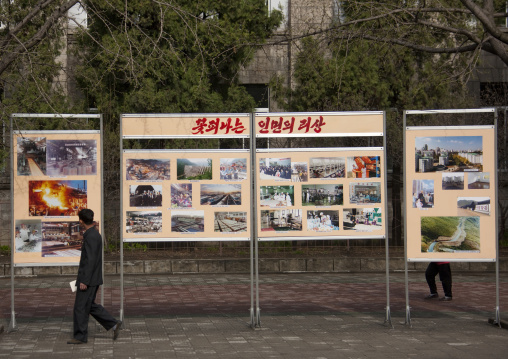 North Korean man passing in front of a propaganda billboard about industry, Pyongan Province, Pyongyang, North Korea