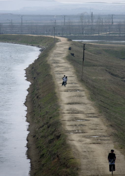 North horean people riding bicycles along a river in the countryside, Pyongan Province, Pyongyang, North Korea