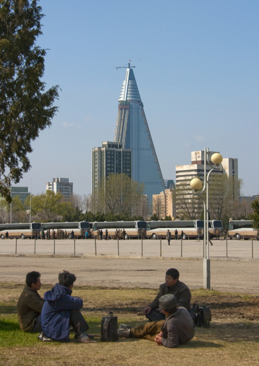 North Korean people resting in a park in front of the pyramid-shaped Ryugyong hotel, Pyongan Province, Pyongyang, North Korea