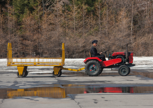 Tractor trailer and driver at Samjiyon airport airfield going to pick up the tourists luggages, Ryanggang Province, Samjiyon, North Korea