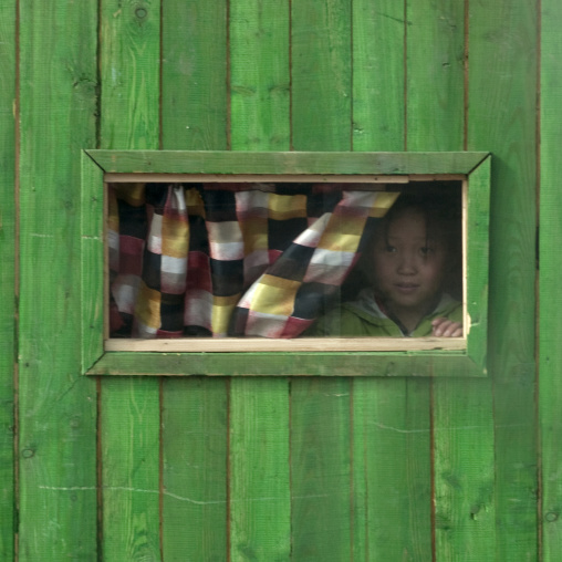 North Korean girl looking thru the window of a small green shop, Ryanggang Province, Samjiyon, North Korea