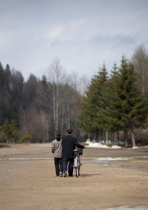Rear view of a North Korean couple with a bicycle, Ryanggang Province, Rimyongsu, North Korea
