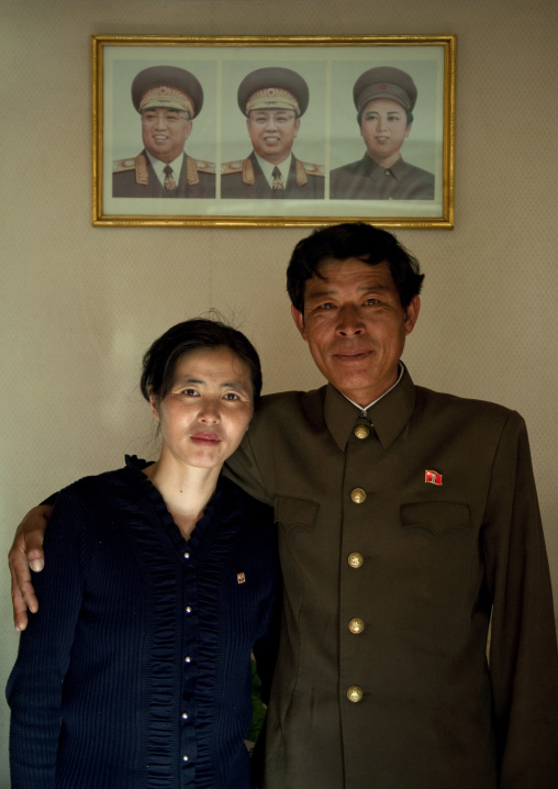 North Korean couple posing in front of the official portraits of the Dear Leaders, North Hamgyong Province, Jung Pyong Ri, North Korea