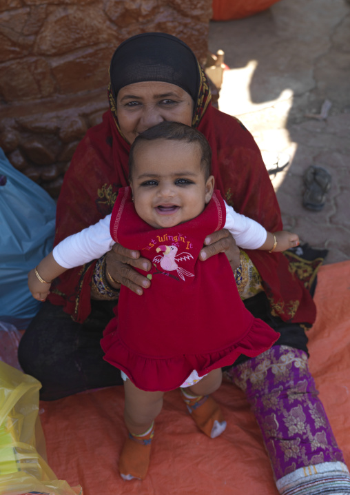 A Smiling Bedouin Baby Being Held By Her Mother, Ibra, Oman