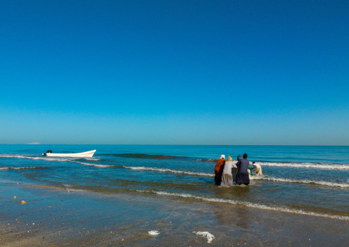 Omani fishermen pushing a boat in the sea, Al Batinah, Barka, Oman