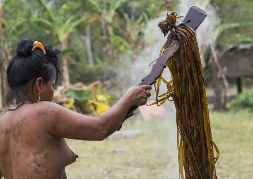 Panama, Darien Province, Puerta Lara, Wounaan Tribe Woman Usinf A Special Wood Stick To Dye Clothes