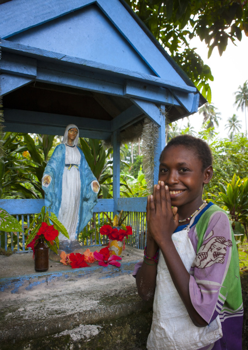 Young girl praying in front of virgin maria statue, New Ireland Province, Langania, Papua New Guinea
