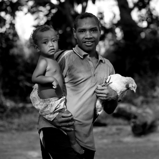 Man carrying his son and a chicken, Milne Bay Province, Trobriand Island, Papua New Guinea