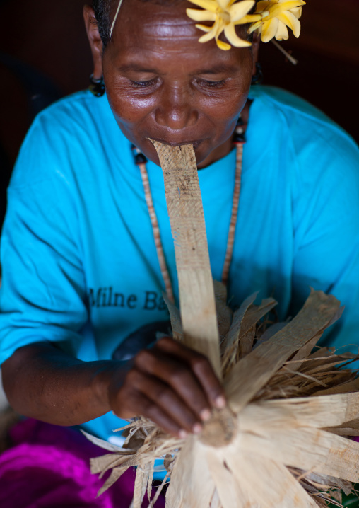 Woman making a traditional skirt with pandanus and banana leaves, Milne Bay Province, Trobriand Island, Papua New Guinea