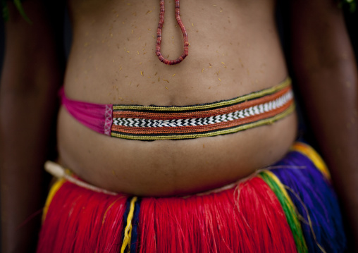 Woman wearing a traditional red skirt made with pandanus and banana leaves, Milne Bay Province, Trobriand Island, Papua New Guinea