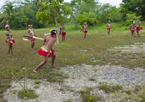Girls in traditional clothing playing cricket, Milne Bay Province, Trobriand Island, Papua New Guinea