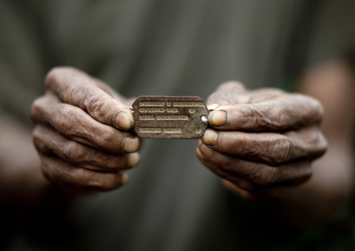 Man holding a WW2 Dog Tag, Milne Bay Province, Trobriand Island, Papua New Guinea