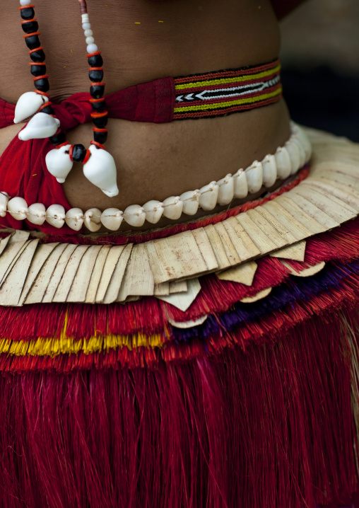 Woman wearing a traditional red skirt made with pandanus and banana leaves, Milne Bay Province, Trobriand Island, Papua New Guinea