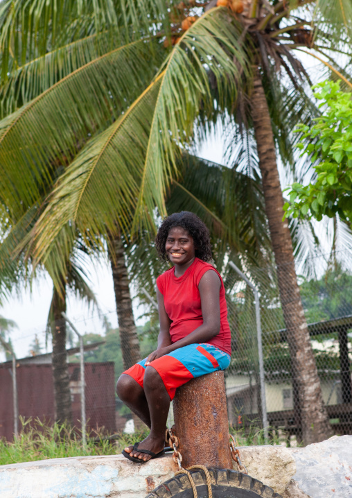 Smiling young woman sit under a palm tree, Autonomous Region of Bougainville, Bougainville, Papua New Guinea