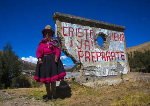 Perivian Woman In Front Of A Catholic Slogan, Cuzco, Peru