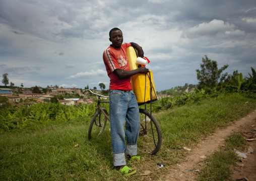Rwandan man putting a jerrycan on his bicycle, Kigali Province, Kigali, Rwanda