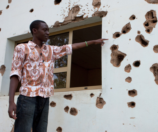 Rwandan man showing bullets holes in camp kigali memorial site, Kigali Province, Kigali, Rwanda
