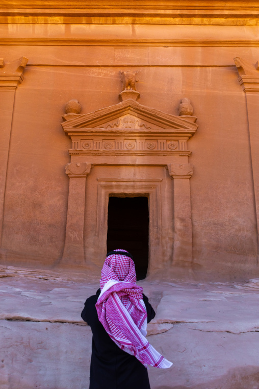Saudi tourist in front of a tomb in al-Hijr archaeological site in Madain Saleh, Al Madinah Province, Alula, Saudi Arabia