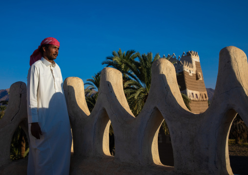 Saudi man standing on the crenelated terrace of his mud house, Najran Province, Najran, Saudi Arabia