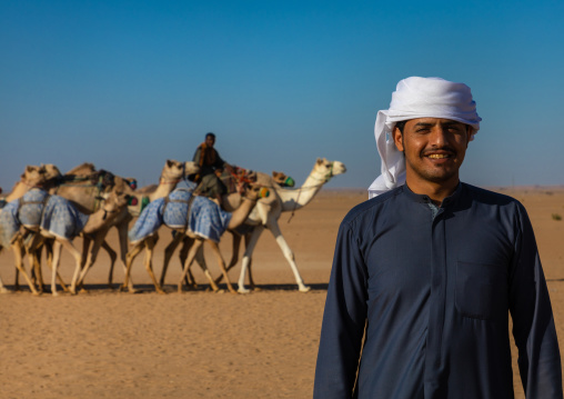 Saudi man in front of camels training for race in the Rub' al Khali desert, Najran province, Hubuna, Saudi Arabia