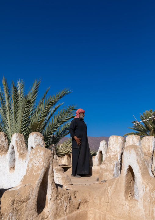 Saudi farmer standing on the terrace of a traditional old mud house, Najran Province, Najran, Saudi Arabia