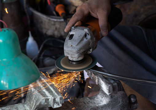 A saudi man prepares a traditional janbiya dagger for sale inside his shop, Najran Province, Najran, Saudi Arabia