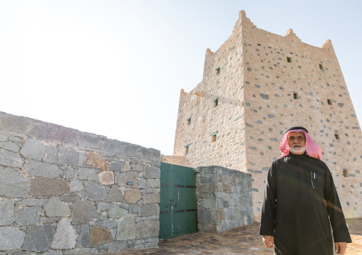 Saudi man standing in front of an old traditional stone house, Asir province, Al-Namas, Saudi Arabia
