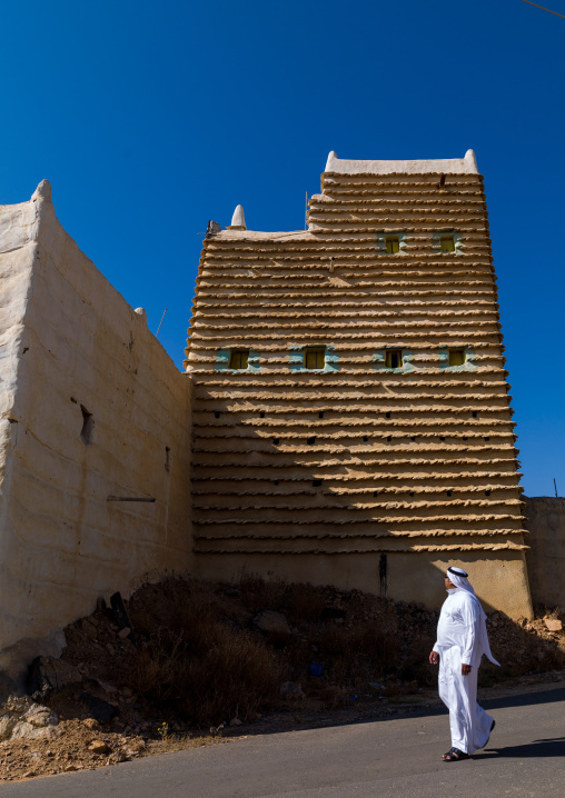 Saudi man in front of traditional clay and silt homes in a village, Asir Province, Ahad Rafidah, Saudi Arabia