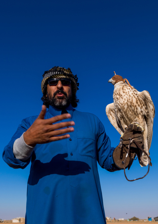 Saudi man with falcon perching on hand, Al-Jawf Province, Sakaka, Saudi Arabia