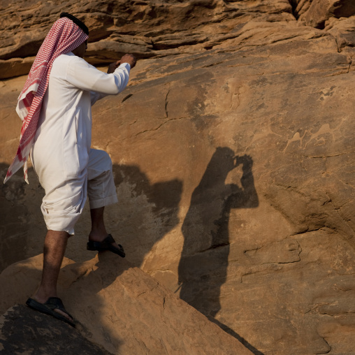 Saudi tourist taking pictures of petroglyphs on a rock, Najran Province, Abar Himma, Saudi Arabia