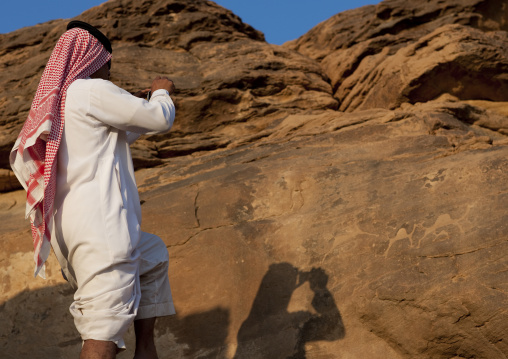 Saudi tourist taking pictures of petroglyphs on a rock, Najran Province, Abar Himma, Saudi Arabia