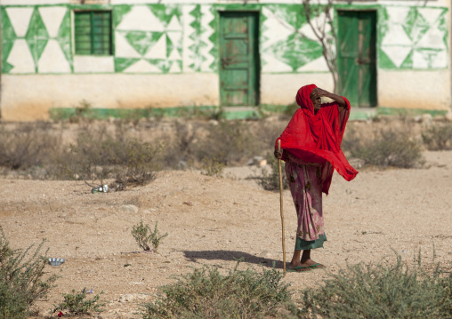 A Senior Woman Wearing A Bright Red Shawl And Holding A Stick Looking At The Horizon , Somaliland