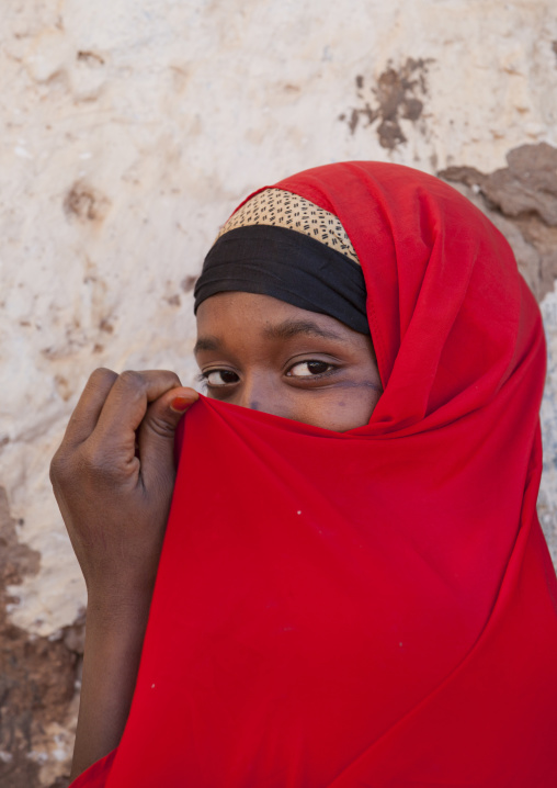 Portrait Of A Teenage Girl Wearing A Red Hijab Hiding Her Mouth In Her Hijab, Baligubadle, Somaliland