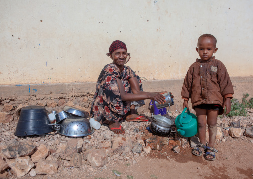 Somali mother with her son washing kitchen tools outside of her home, Woqooyi Galbeed province, Baligubadle, Somaliland
