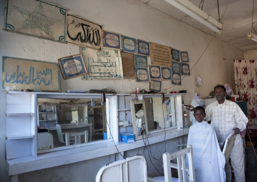 Interior Of Barber Shop With A Young Boy In A While Shawl Getting A Hair Cut By An Adult Hairdresser, Boorama, Somaliland