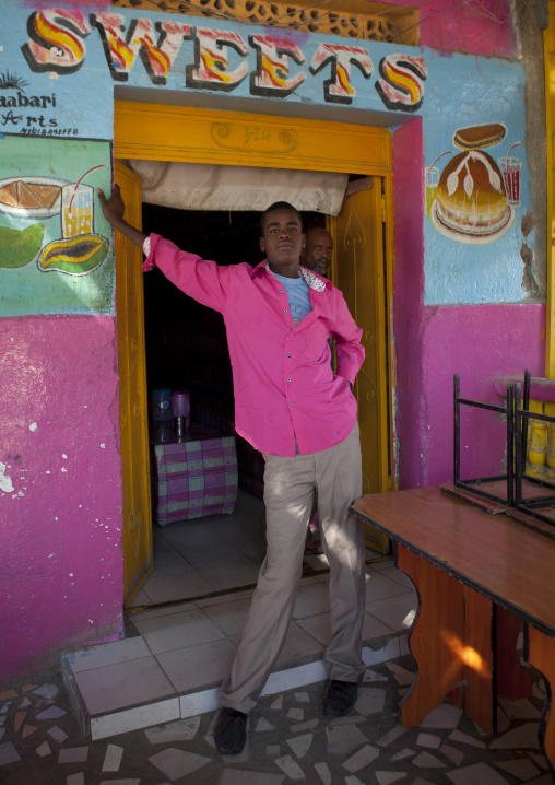 A Young Man Wearing A Pink Shirt Standing In The Door Frame Of A Sweets Shop, Boorama, Somaliland