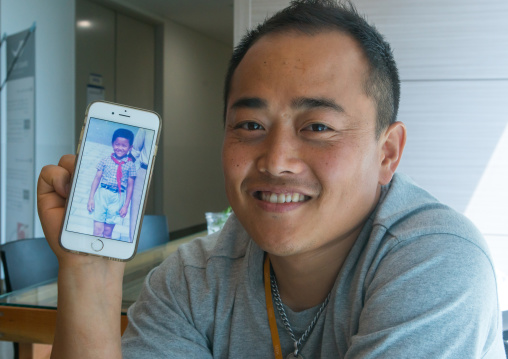 North korean defector joseph park in yovel cafe showing a picture of himself taken in north korea, National capital area, Seoul, South korea