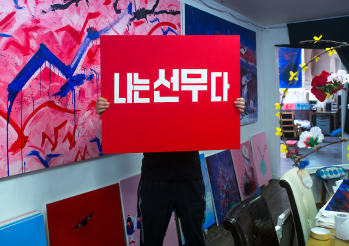 Sun mu artist hiding behind one of his painting, National capital area, Seoul, South korea