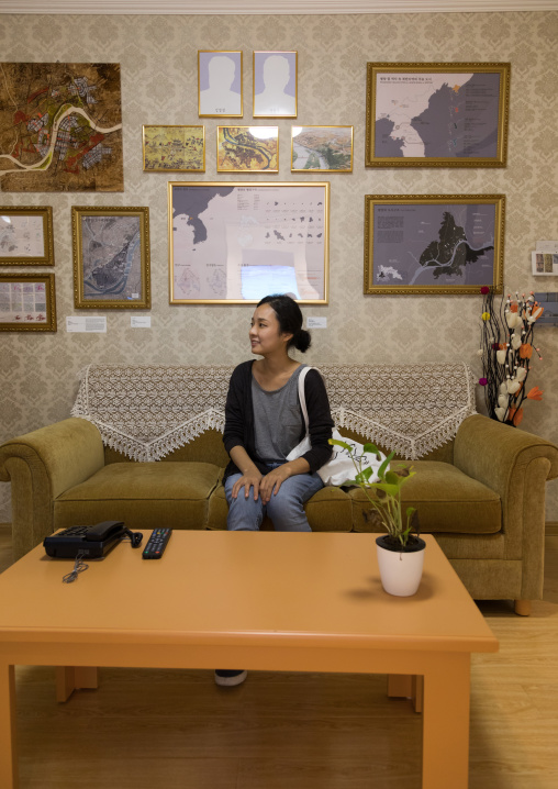 South Korean visitor sit below the portraits of the dear leaders with the pictures removed during the exhibition Pyongyang sallim showing a north Korean apartment replica, National Capital Ar