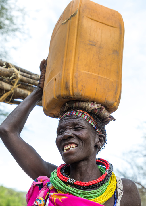 Smiling Toposa tribe woman carrying a jerrycan on her head, Namorunyang State, Kapoeta, South Sudan