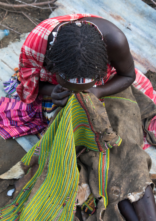 Toposa woman sewing a traditional skirt, Namorunyang State, Kapoeta, South Sudan