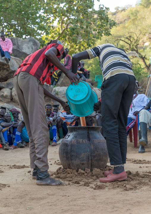 Larim tribe men putting alcohol in a jar during a wedding ceremony, Boya Mountains, Imatong, South Sudan