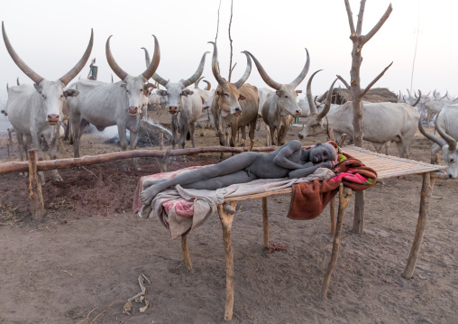 Mundari tribe boy resting on a bed in the early morning in a cattle camp, Central Equatoria, Terekeka, South Sudan