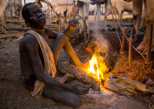 Mundari tribe boy making a campfire with dried cow dungs to repel flies and mosquitoes, Central Equatoria, Terekeka, South Sudan